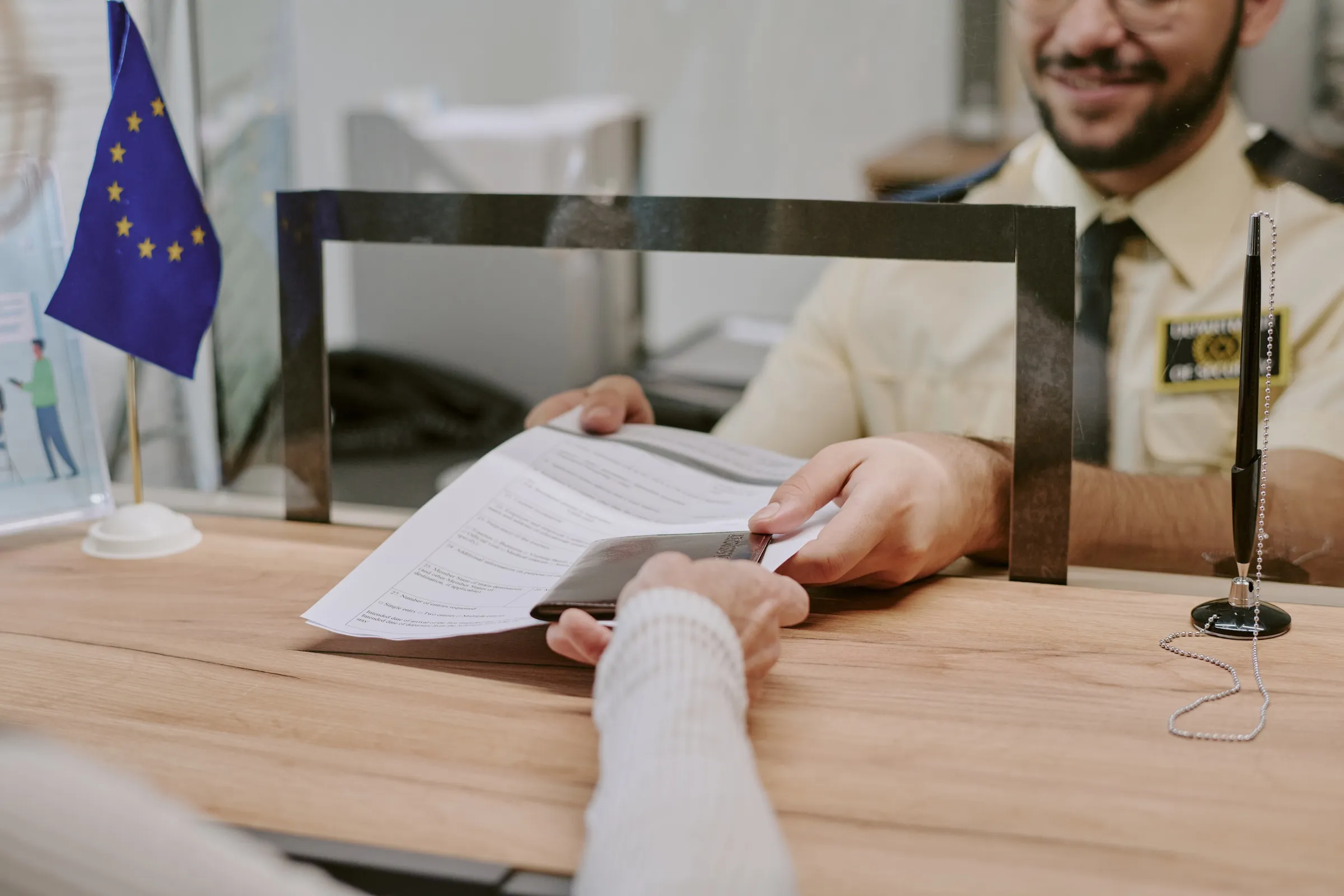 A person at a French consulate counter handing over visa application documents