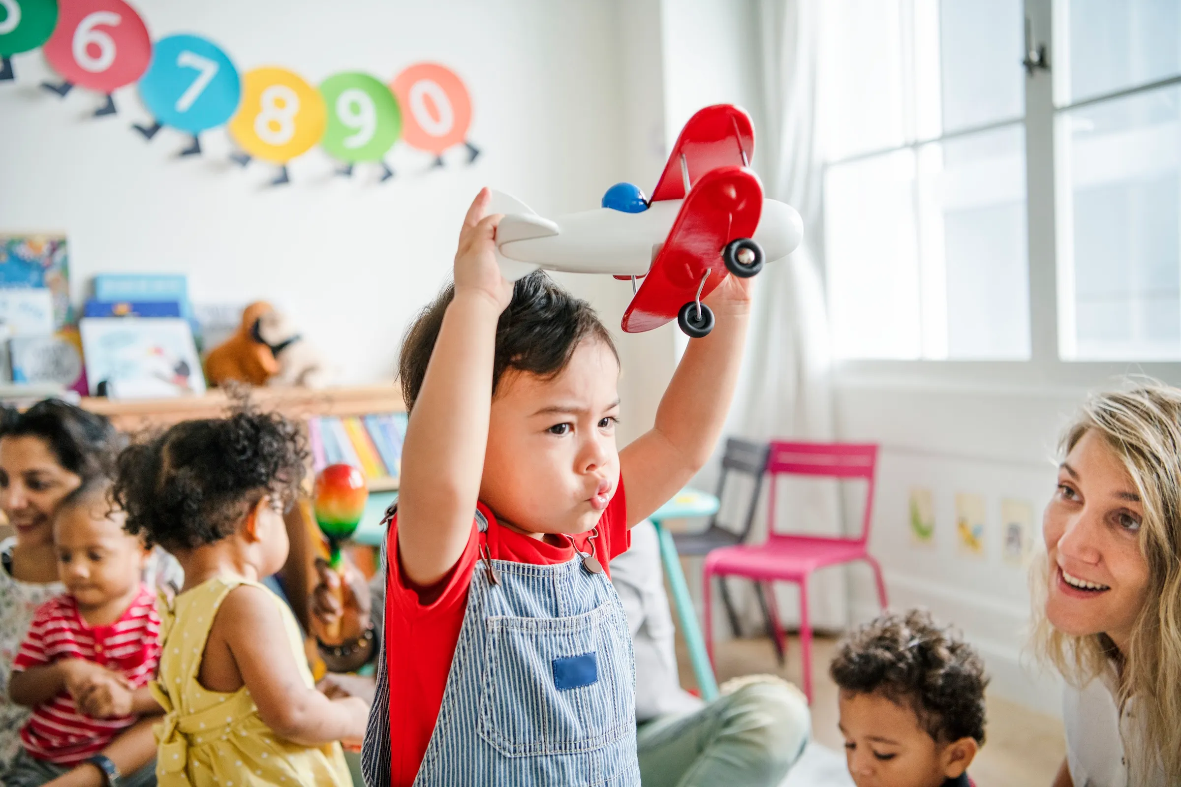 A preschooler enjoying playing with his airplane toy at a Paris daycare